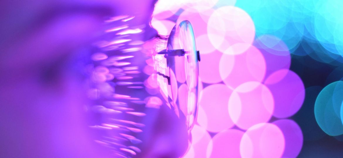 Close-up photo of eyeglasses with bright purple and blue bokeh lights creating an abstract aesthetic.